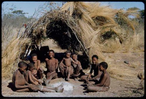 Groups, Extended Family: Gau's family sitting in front of a skerm (left to right): ≠Toma, !Naishi, Be their mother, Gau, /Qui held by Khuan//a (Gau's second wife), /Gunda (husband of N!ai and son of Khuan//a by a former marriage with Bo) and ≠Gao (son of Gau and Be)