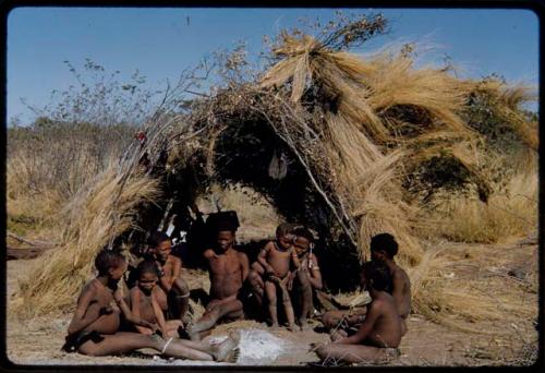 Groups, Extended Family: Gau's family sitting in front of a skerm (left to right): ≠Toma, !Naishi, Be their mother, Gau, /Qui held by Khuan//a (Gau's second wife), /Gunda (husband of N!ai and son of Khuan//a by a former marriage with Bo) and ≠Gao (son of Gau and Be)