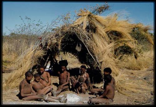 Groups, Extended Family: Gau's family sitting in front of a skerm (left to right): ≠Toma, !Naishi, Be their mother, Gau, /Qui held by Khuan//a (Gau's second wife), /Gunda (husband of N!ai and son of Khuan//a by a former marriage with Bo) and ≠Gao (son of Gau and Be)