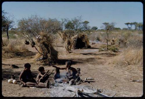 Groups, Extended Family: ≠Toma working on arrows, sitting with !U and their children, with /Qui and //Kushay's skerm and "Old Gau's" skerm in the background