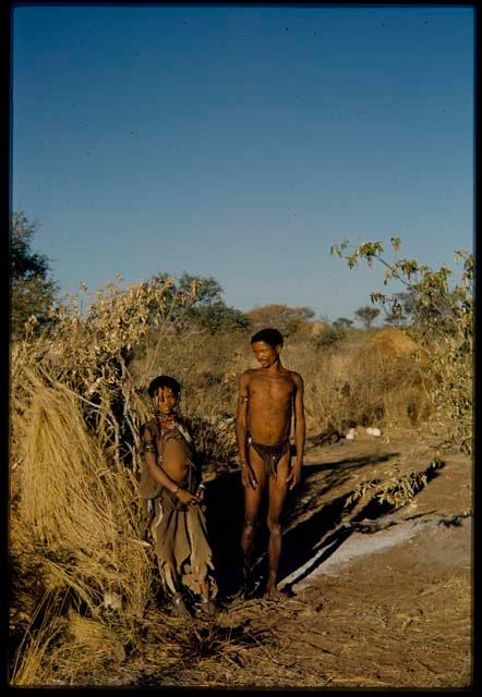 Groups, "Nuclear Family": "/Gao Music" and his wife, ≠Nisa (daughter of "Gao Medicine), standing in front of a skerm