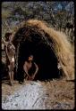 Groups, "Nuclear Family": Tsamgao sitting in front of a skerm, with Bau (daughter of /Ti!kay) standing next to him.