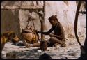 Woman sitting and using a churn at William Hartley's waterhole