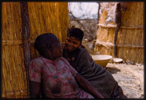 Two women sitting against a hut in hunting camp