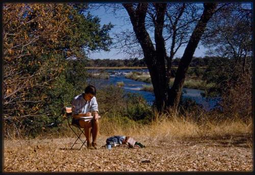 Deborah Marshall sitting in a chair and sketching by river