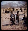 Two women dancing after ostrich hunting, with other people watching them