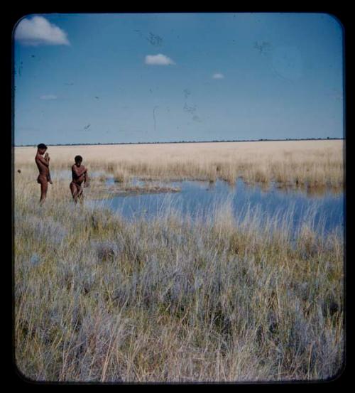 Two men standing at edge of pan; one of them is ≠Toma