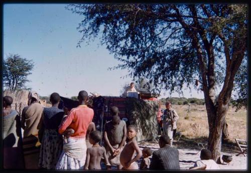 Nicholas England standing in a truck for recording, surrounded by a group of people