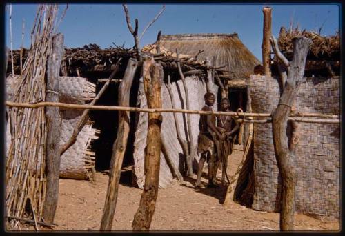 Village huts, showing mats and roof line, with two people in the background