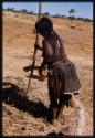 Woman threshing, seen from behind