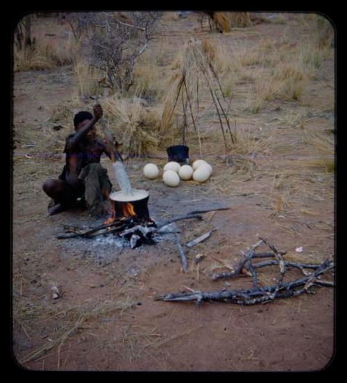 Man squatting and cooking ostrich eggs