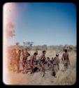 Group of men performing a curing dance, with a circle of women sitting