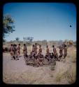 Group of men performing a curing dance, with a circle of women sitting