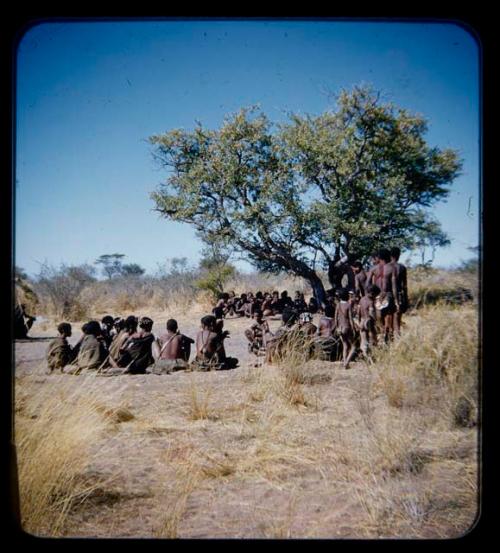 Group of men performing a curing dance, with a circle of women sitting