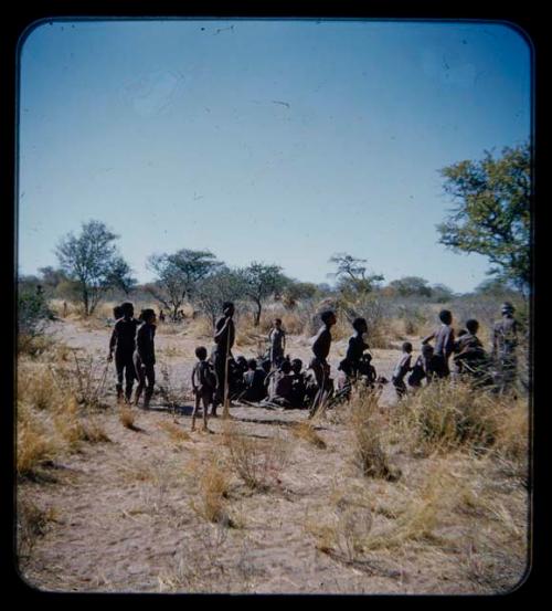 Group of men performing a curing dance, with a circle of women sitting