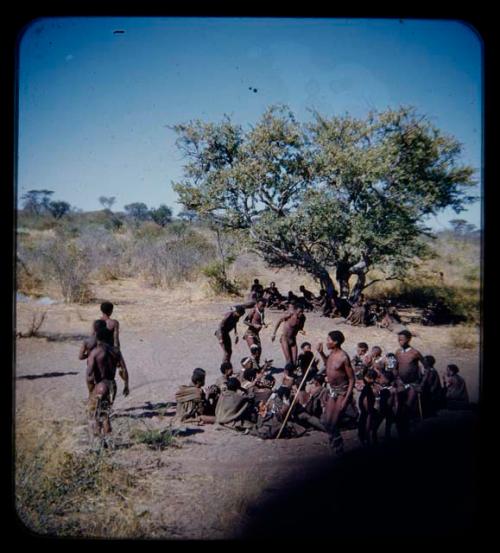 Group of men performing a curing dance, with a circle of women sitting