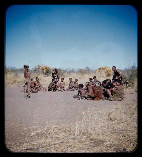 Circle of women with boys wearing dance rattles, gathered for a curing dance