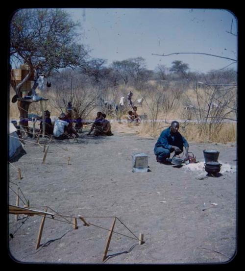 Philip Hameva squatting, with other expedition members and a group of people in the background