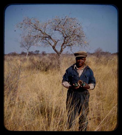 Philip Hameva holding fruit, with a tree behind him