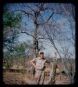 Charles Handley standing next to a dead leopard hung from tree