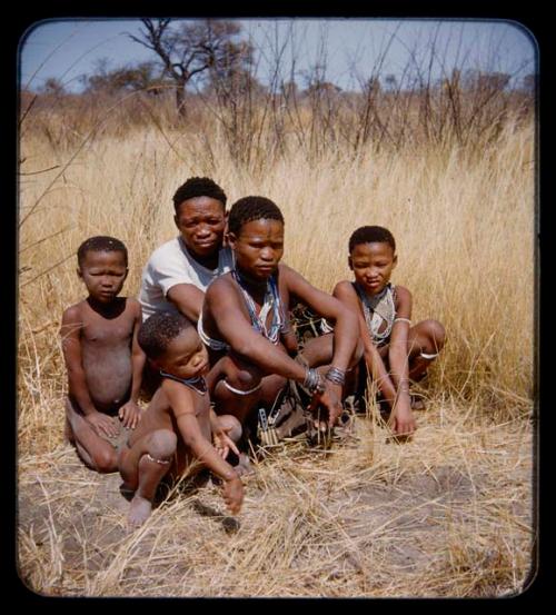 Groups: Man wearing T-shirt, woman, and three children sitting