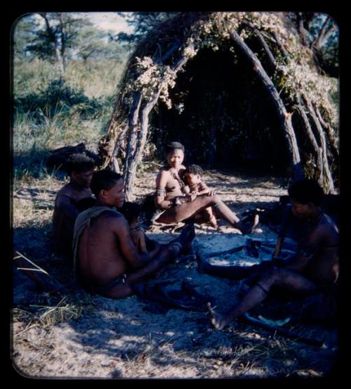 Groups: Four women sitting by a skerm; three with babies and one with mortar and pestle