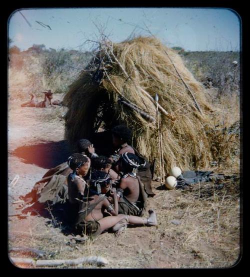 Groups: Group of women and children sitting by a skerm, with two ostrich eggs on the ground nearby