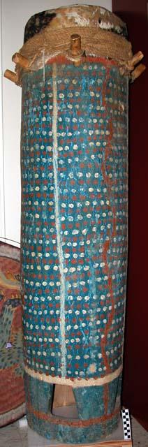 Tall drum, painted blue, red, and white, of hide, wooden pegs, and fiber