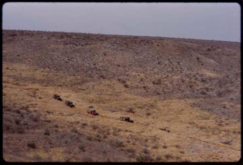 Expedition trucks driving through the landscape, seen from a distance