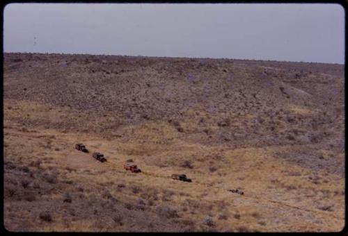 Expedition trucks driving through the landscape, seen from a distance