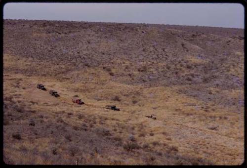 Expedition trucks driving through the landscape, seen from a distance