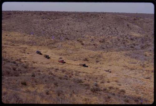 Expedition trucks driving through the landscape, seen from a distance