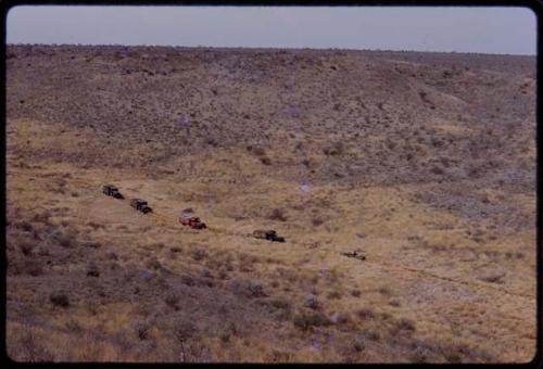 Expedition trucks driving through the landscape, seen from a distance