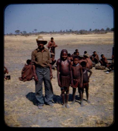 Man and children standing, people sitting in the background