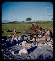 Makiena (wife of Muremi) standing and getting water at a waterhole, with Rungiero (her son's wife), Rungiero's sister and a child (possibly Namvoura, Muremi's granddaughter) watching her