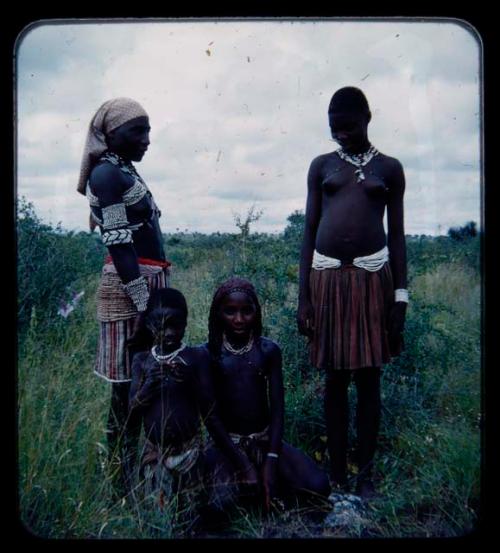 Makiena (wife of Muremi) standing with Rungiero (her son's wife), with Rungiero's sister and a child (possibly Namvoura, Muremi's granddaughter) sitting next to them