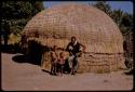 Man standing with his sons by a hut