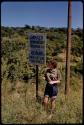 Elizabeth Marshall Thomas standing by a sign on a bridge