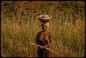 Woman walking on a road, carrying a basket on her head