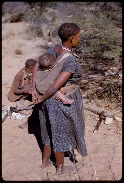 Woman wearing a blue dress, baby on her back