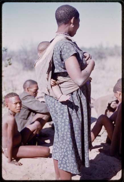 Woman wearing a blue dress carrying a baby on her back