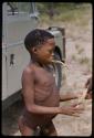 Boy standing by a truck, with fiber in his mouth