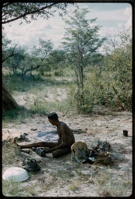 Man sitting on the ground, with a dog beside him