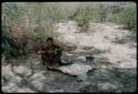 Man sitting beside an animal hide