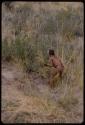 Boy gathering grass, seen from behind