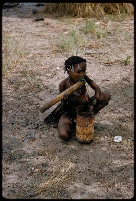 Girl eating raw green leaves that she has pounded in a mortar