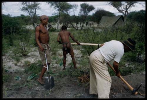 Three men, including Ti!kay and Wilhelm Camm, clearing a garden with tools