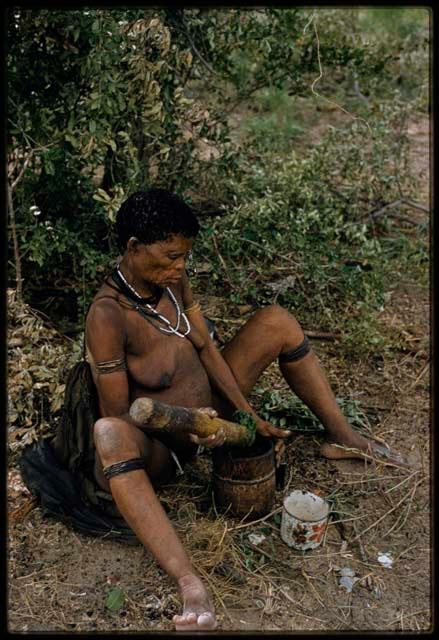 Woman sitting and mashing leaves in a mortar