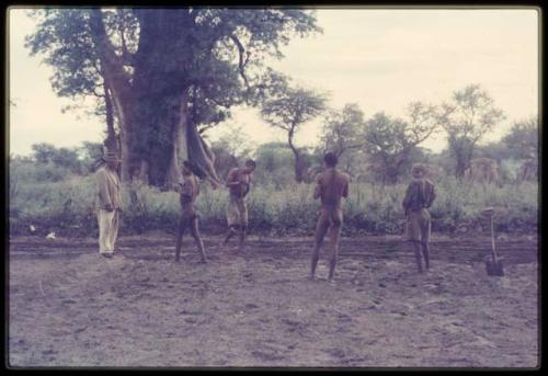 Five men, including Wilhelm Camm and /Ti!Kay, standing in a cleared garden