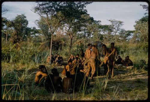 Men performing a curing dance, with a group of people sitting and watching them